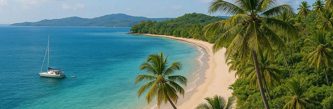 Photo d'une plage paradisiaque à Nosy Be avec un voilier dans les eaux turquoise